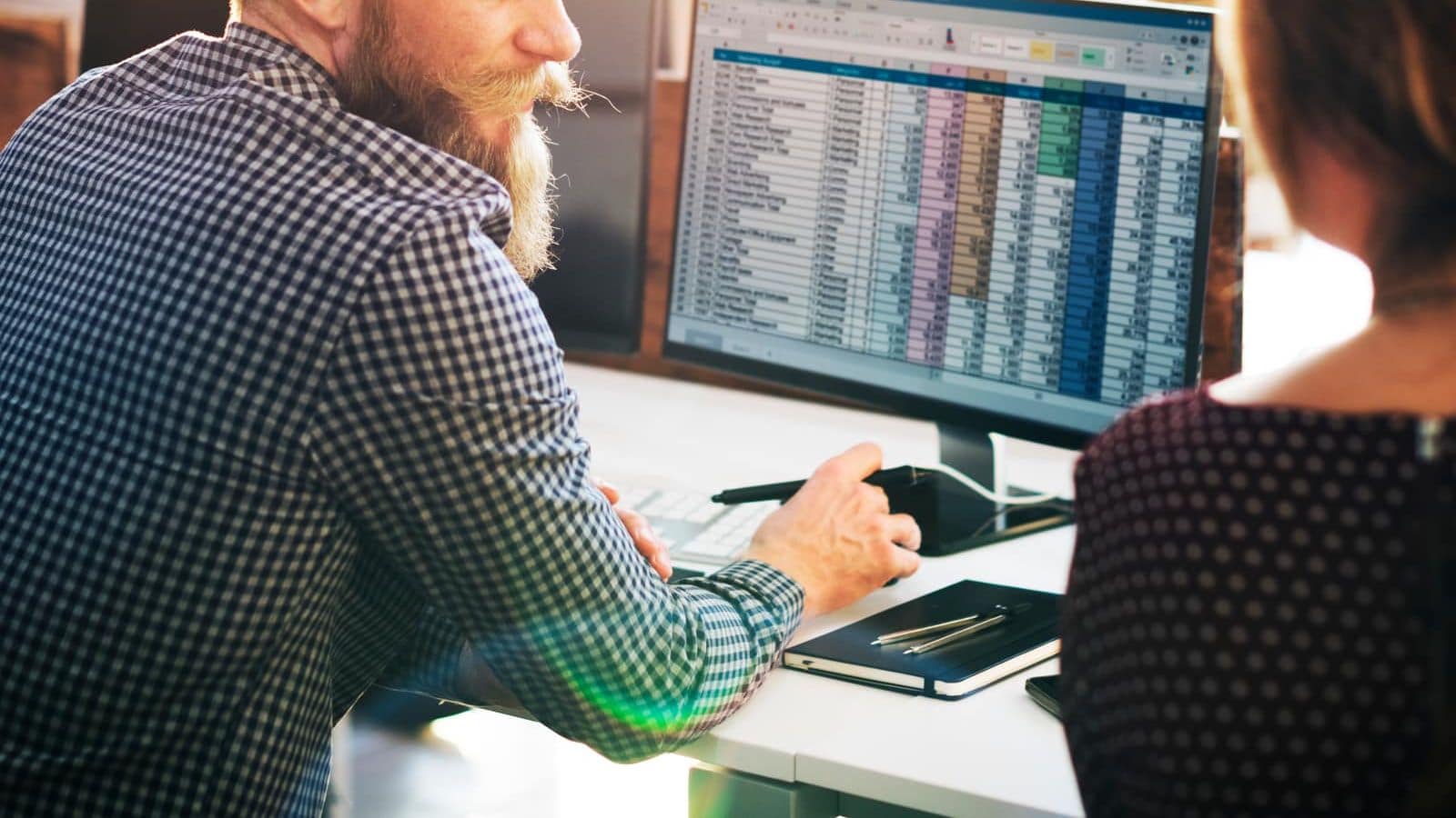 Two colleagues talking beside a computer in an office